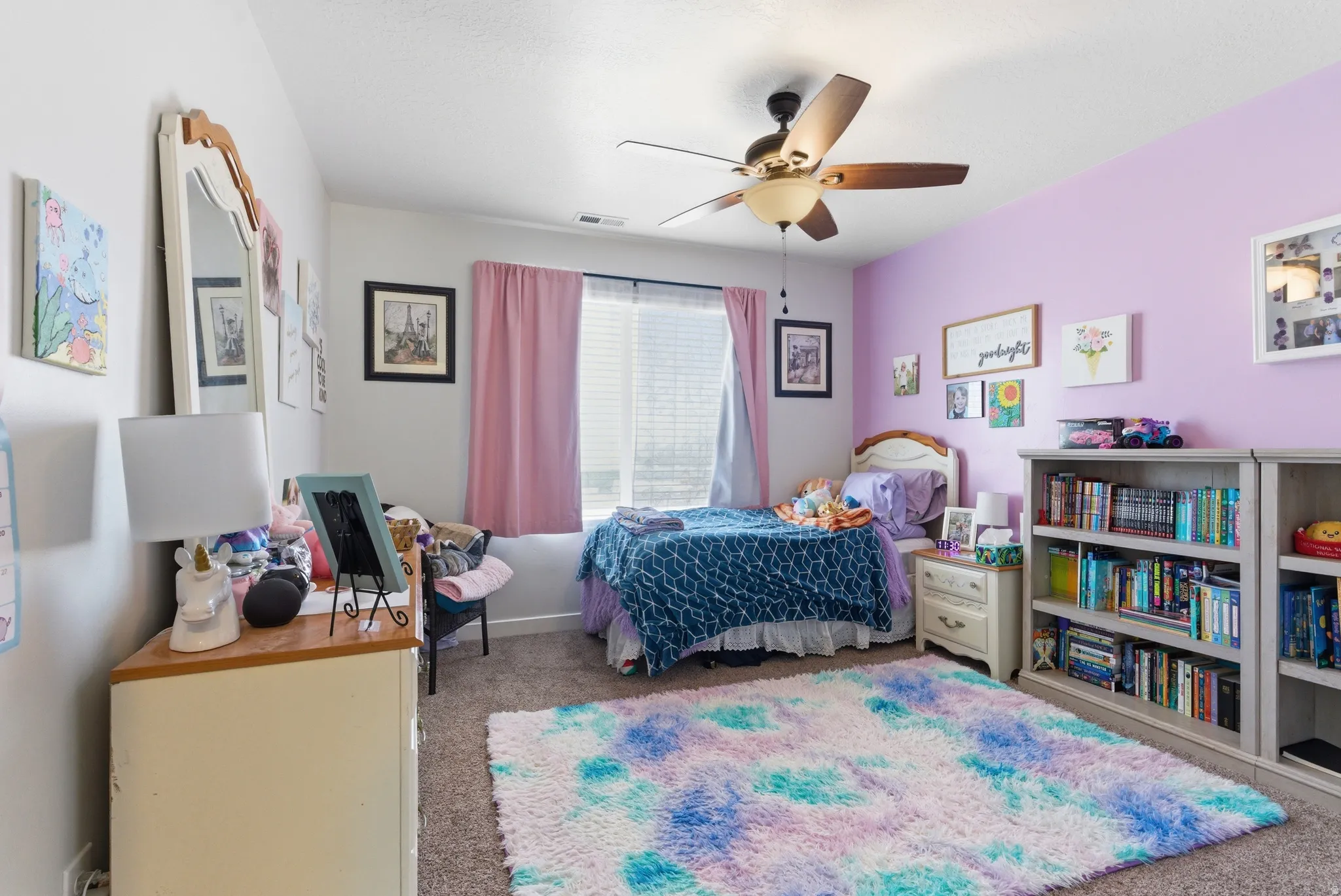 Recessed window with blinds and curtains, ceiling fan with light fixture, built-in shelving, and neutral tone carpeting