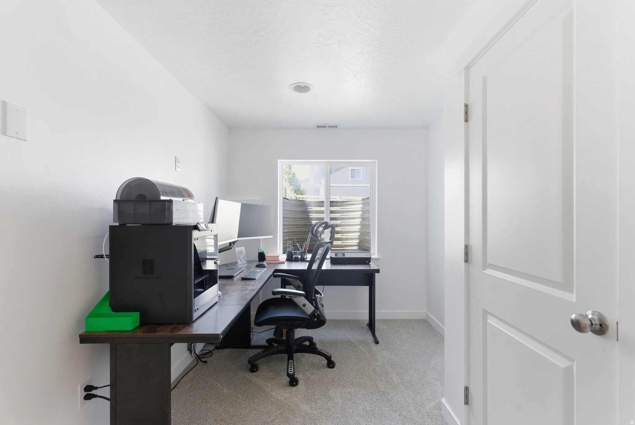 Carpeted room featuring a white paneled door, recessed lighting, and a window