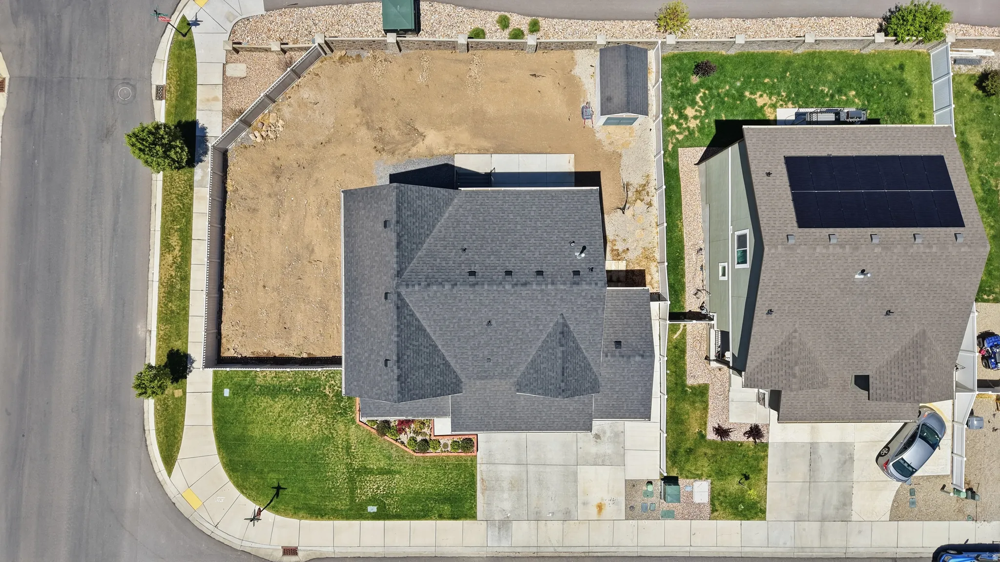 Gabled roofline, concrete driveway, corner lot, established landscaping, and a fenced yard