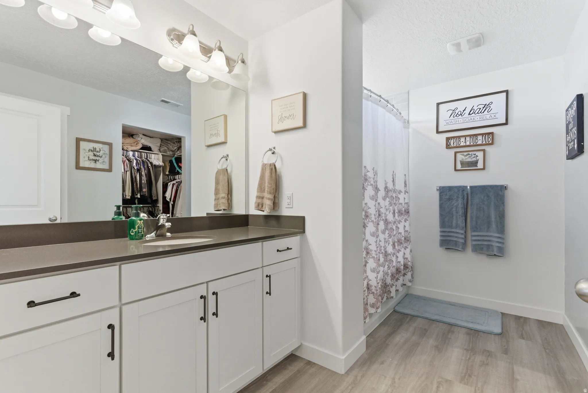 White vanity cabinetry with dark hardware and a contrasting countertop