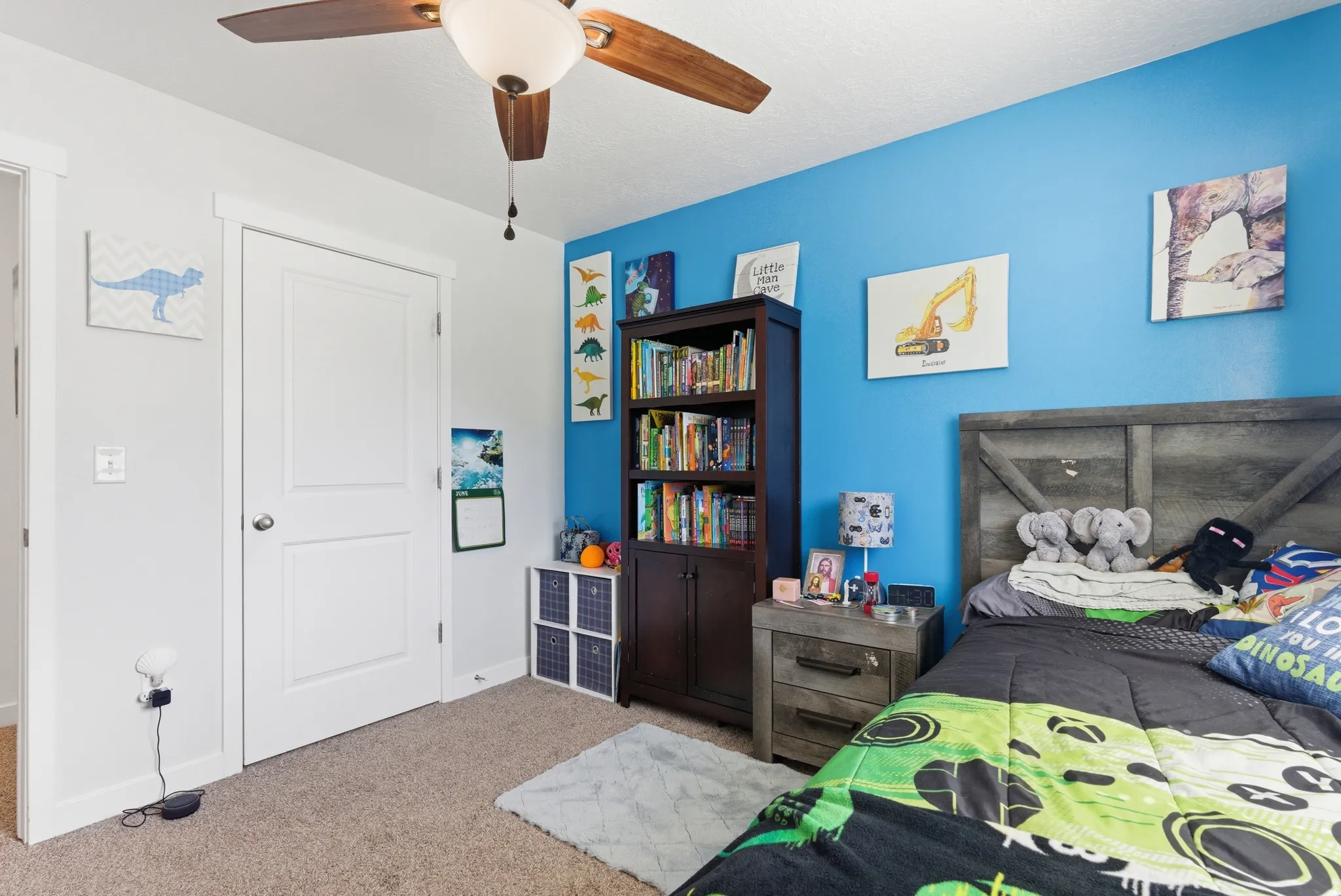 Recessed panel interior door, ceiling fan with integrated lighting, wood-finish headboard, and built-in shelving unit