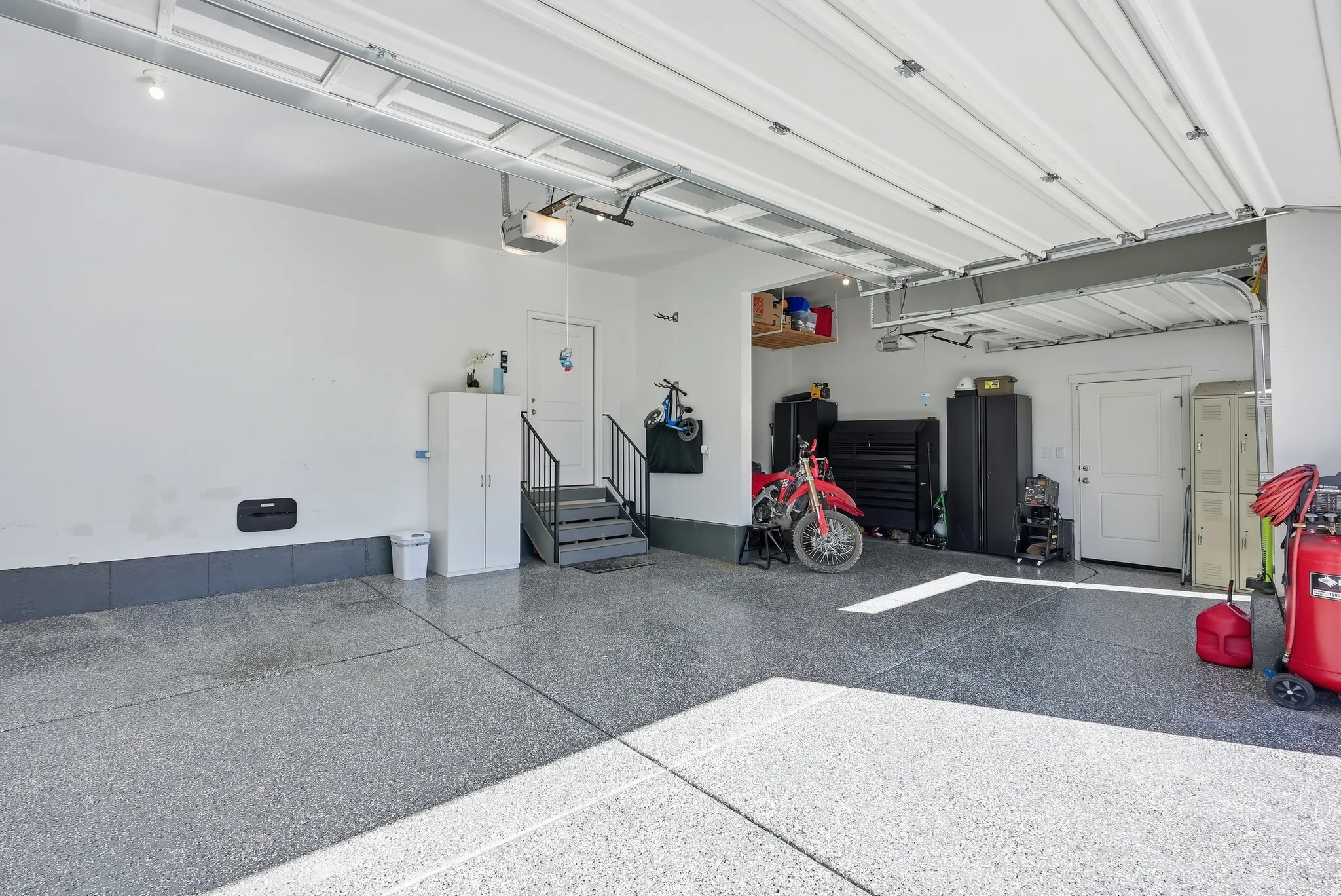 Spacious garage with epoxy flooring, white walls, and a finished ceiling