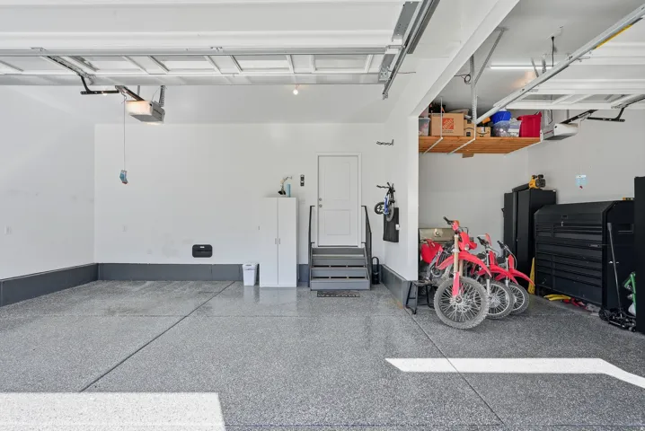 Spacious garage featuring a durable epoxy floor, integrated overhead storage, and an interior access door