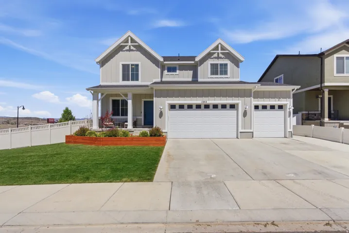 Contemporary two-story residence featuring light gray siding, a covered front porch, and a two-car garage