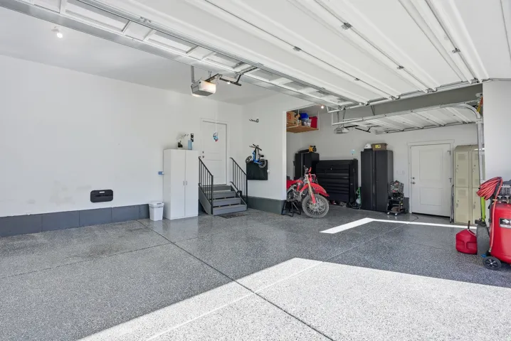 Spacious garage with epoxy flooring, white walls, and a finished ceiling