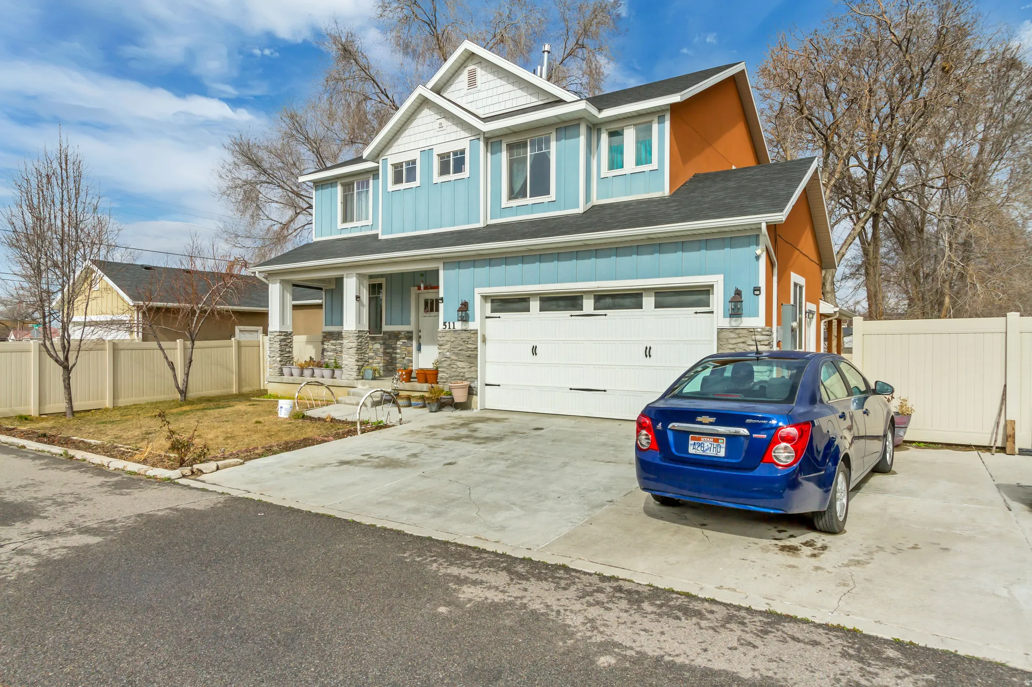 Two-story residence featuring light blue siding with white trim, a stone-clad foundation, and a prominent front porch