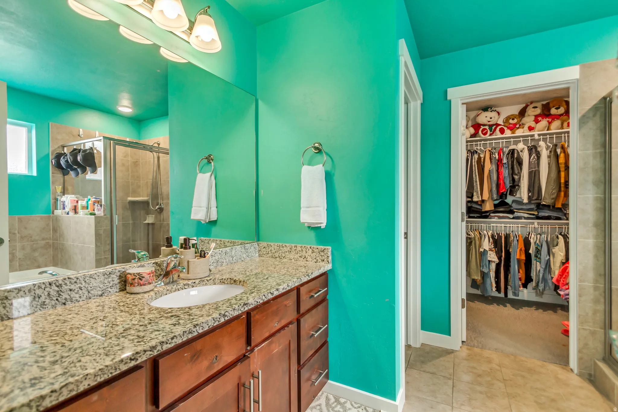 Brown wood-finish vanity with an undermount sink, granite-patterned countertop, and an overhead vanity light fixture