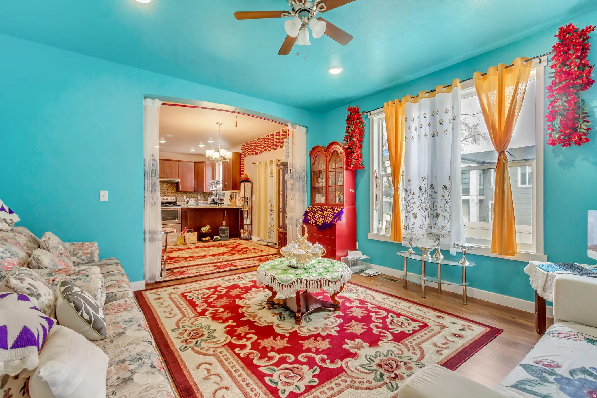 Wood-finish flooring, ceiling fan with integrated lighting, and multiple windows with white trim