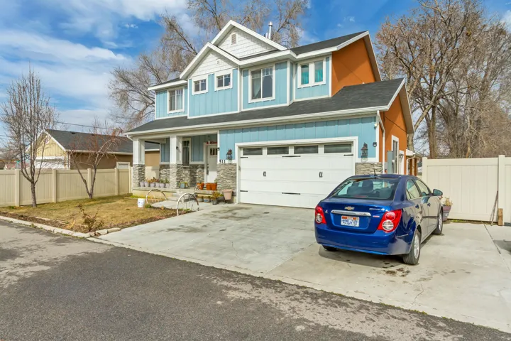 Two-story residence featuring light blue siding with white trim, a stone-clad foundation, and a prominent front porch