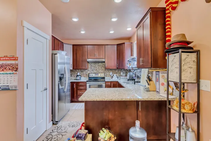 Kitchen featuring wood cabinetry, light-colored countertops, mosaic tile backsplash, and stainless steel appliances