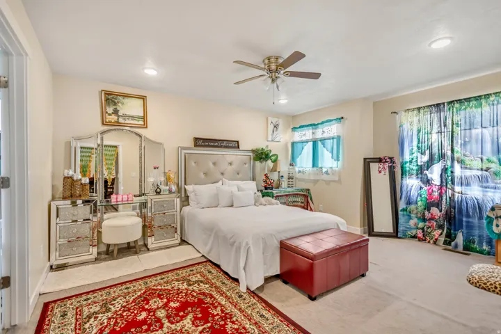 Recessed lighting, ceiling fan, tufted headboard, and light-colored walls