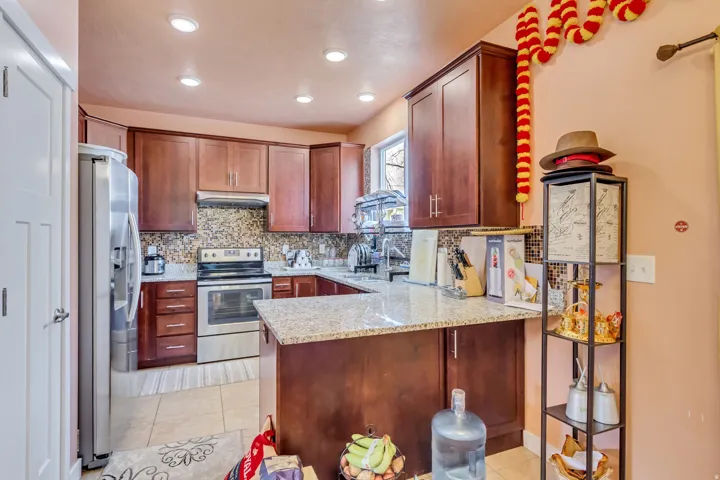Kitchen featuring wood-finish cabinetry, light-toned countertops, and a full suite of stainless steel appliances