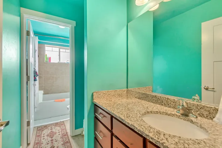 Built-in vanity with a granite-style countertop, undermount sink, and polished chrome faucet