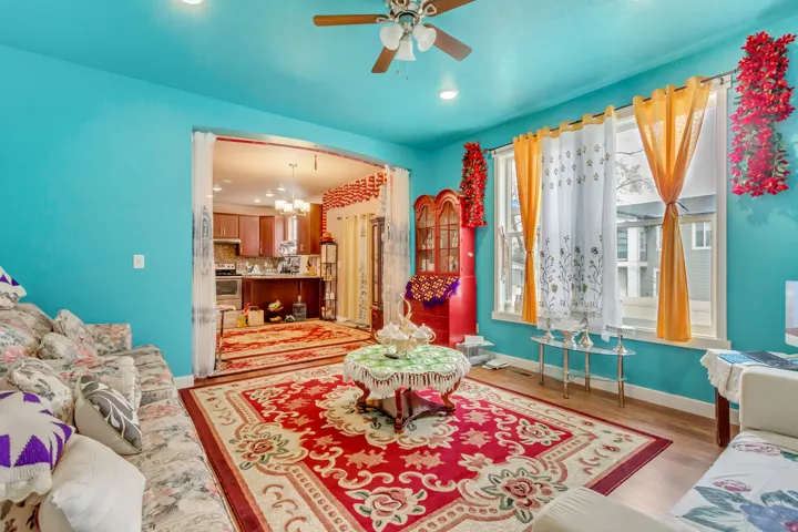 Wood-finish flooring, ceiling fan with integrated lighting, and multiple windows with white trim