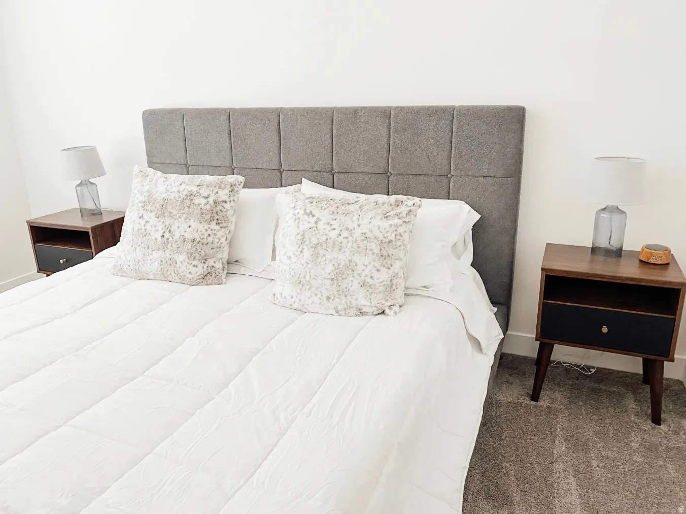 Wall-to-wall carpeting with light-toned walls, featuring a paneled upholstered headboard