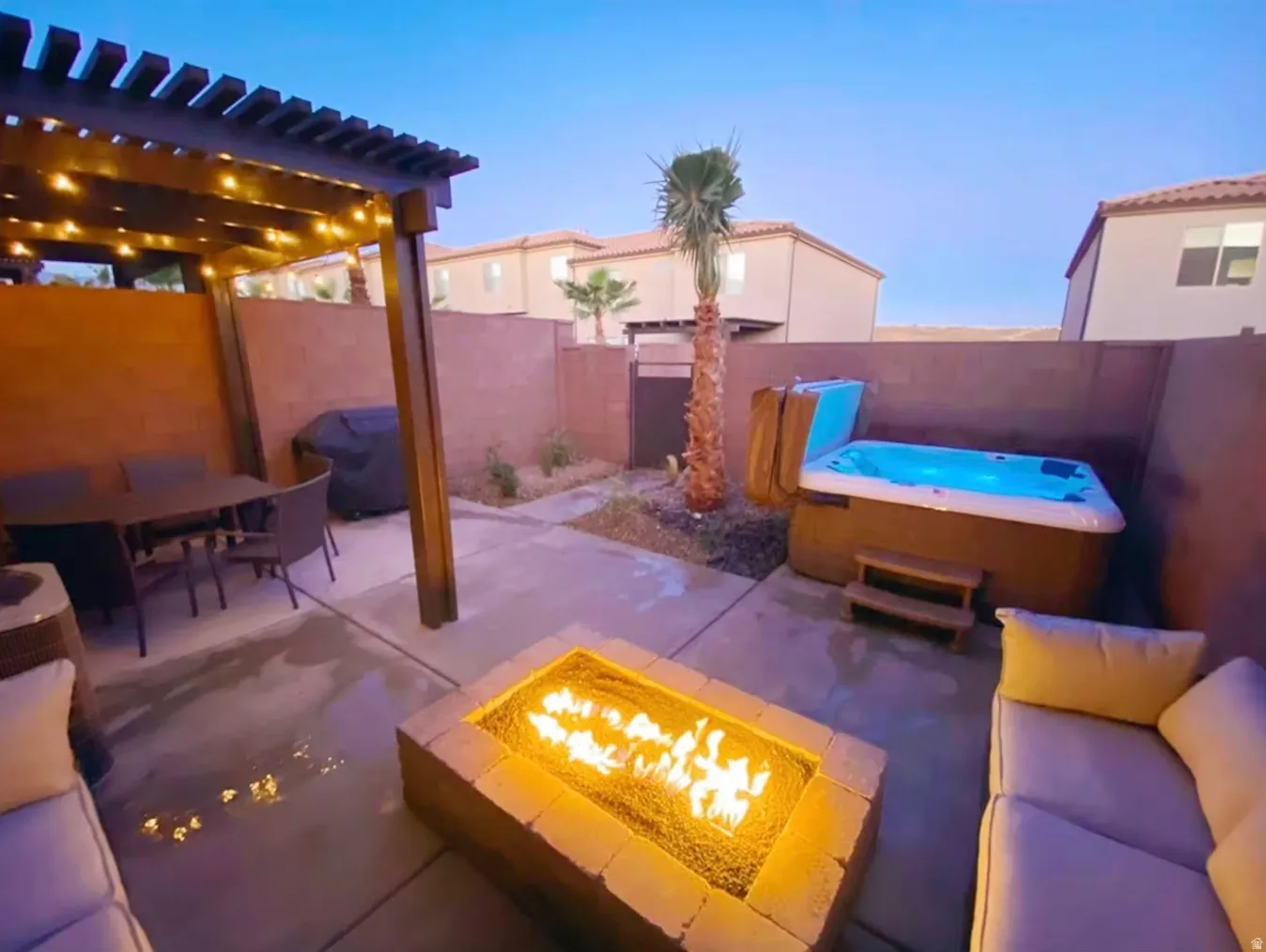 Private patio featuring a built-in hot tub, pergola, fire pit, and privacy walls