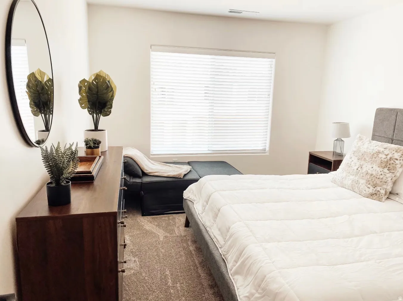 Neutral tone wall finish, large window with blinds, carpeted flooring, and built-in closet