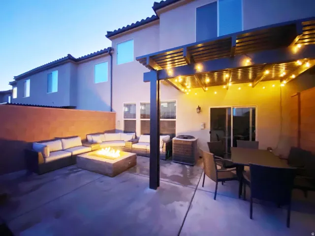 Paved patio with a slatted pergola, built-in fire pit, and sliding glass door access