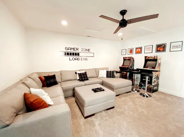 Dedicated recreation room featuring a ceiling fan, recessed lighting, neutral wood-finish flooring, and built-in cabinetry with shelving for gaming consoles and entertainment systems