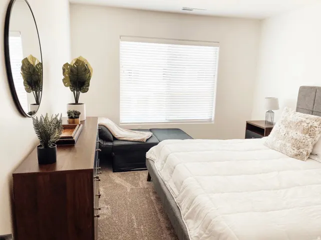 Neutral tone wall finish, large window with blinds, carpeted flooring, and built-in closet