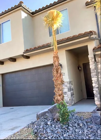 Stucco exterior with stone accents, segmented garage door, and a permanent exterior light fixture