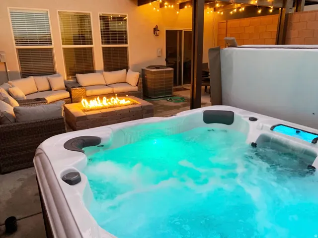 Patio featuring a built-in fire pit, recessed hot tub, and overhead string lighting