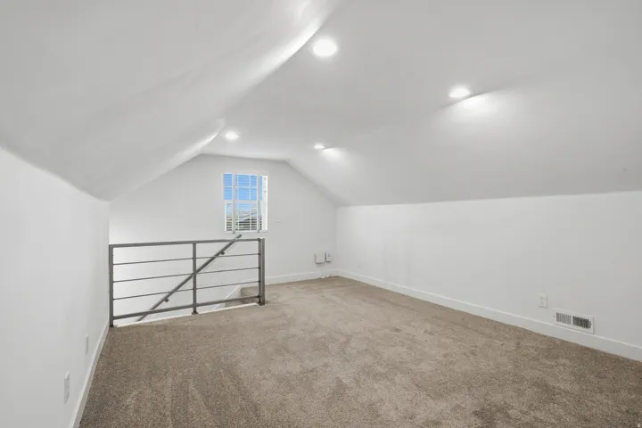 Upstairs living room with vaulted ceiling with recessed lighting, carpeting, a modern metal railing,