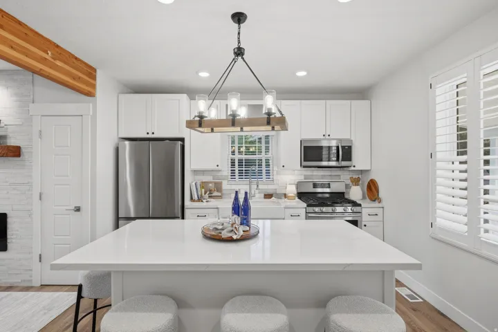 Modern kitchen featuring a white quartz island, stainless steel appliances including a built-in microwave and cooktop, white cabinetry with ample storage