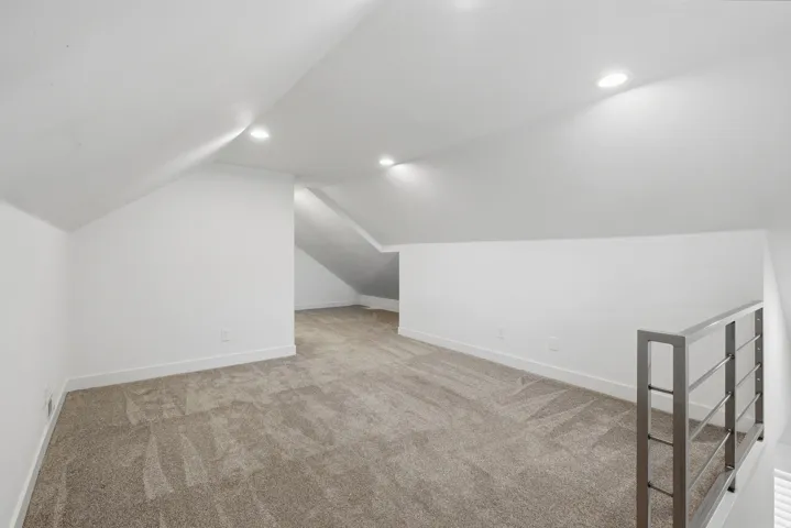 Upstairs living room with vaulted ceiling with recessed lighting, carpeting, a modern metal railing,
