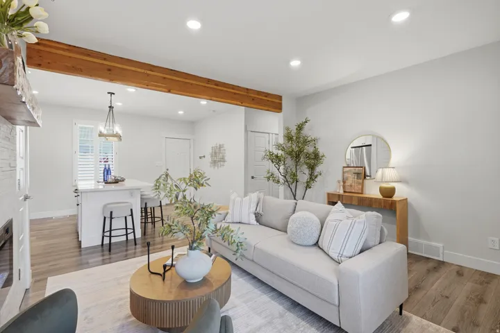 Open-concept living area with a wood ceiling beam, recessed lighting, and wood-finish flooring