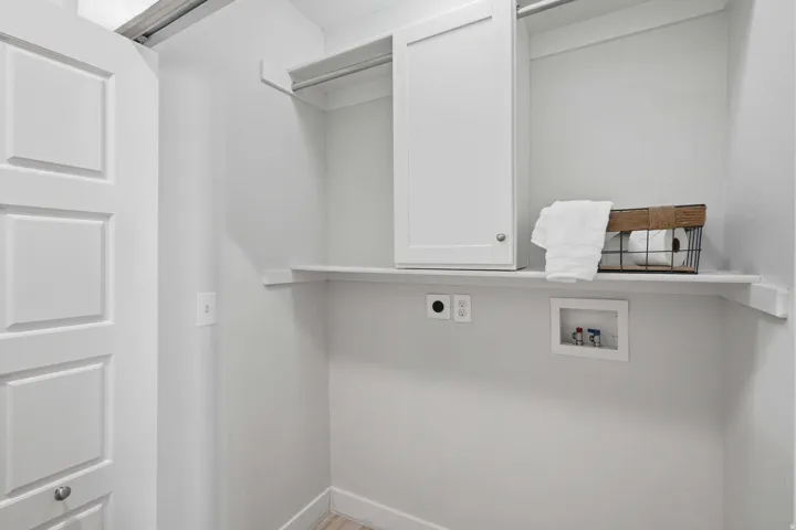Laundry area with upper cabinetry and an open shelf
