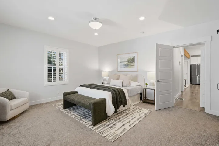 Large primary bedroom with en-suite and large walk-in closet and plantation shutters.