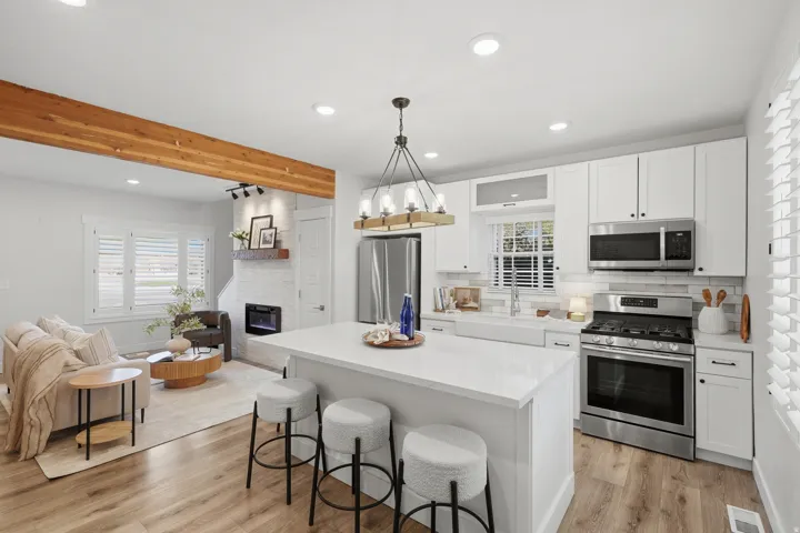 Modern kitchen and dining area featuring white cabinetry, stainless steel appliances, and a large island