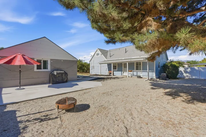 Spacious outdoor area featuring a concrete patio, light-colored gravel, and a covered porch