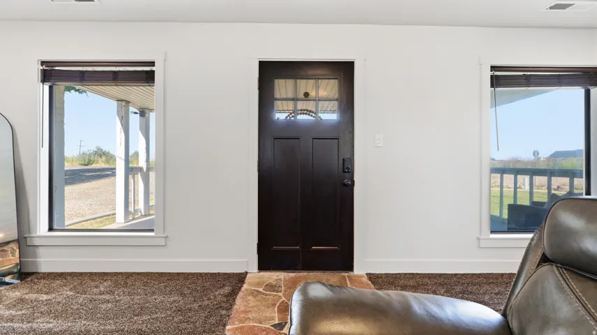 Dark entry door with decorative glass, flanked by two windows with blinds