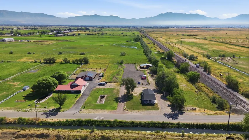 Expansive property featuring multiple structures, mature trees, a driveway, and vast surrounding green acreage