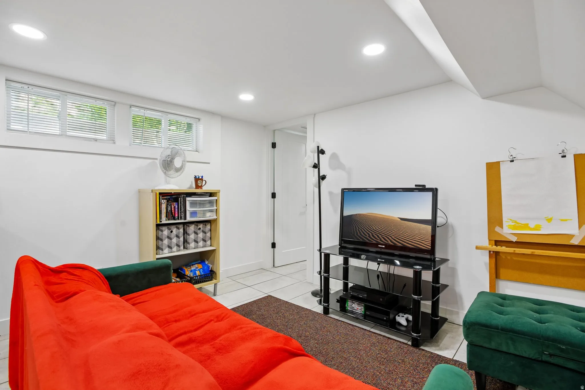 Recessed ceiling lighting, white walls, multiple windows with blinds, tiled flooring, and a white interior door