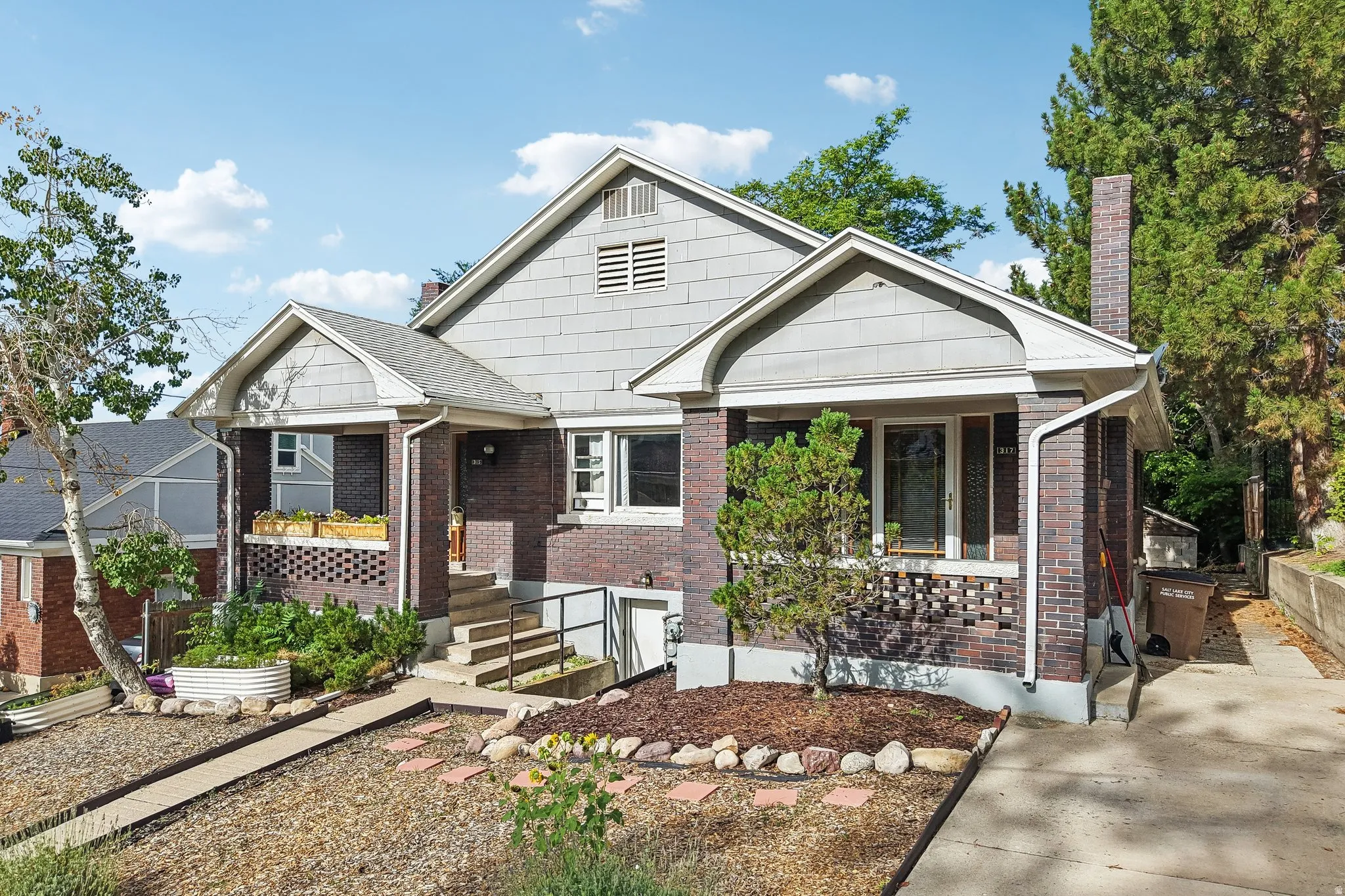 Brick and shingle-sided exterior with a covered front porch, concrete steps, and a paved driveway