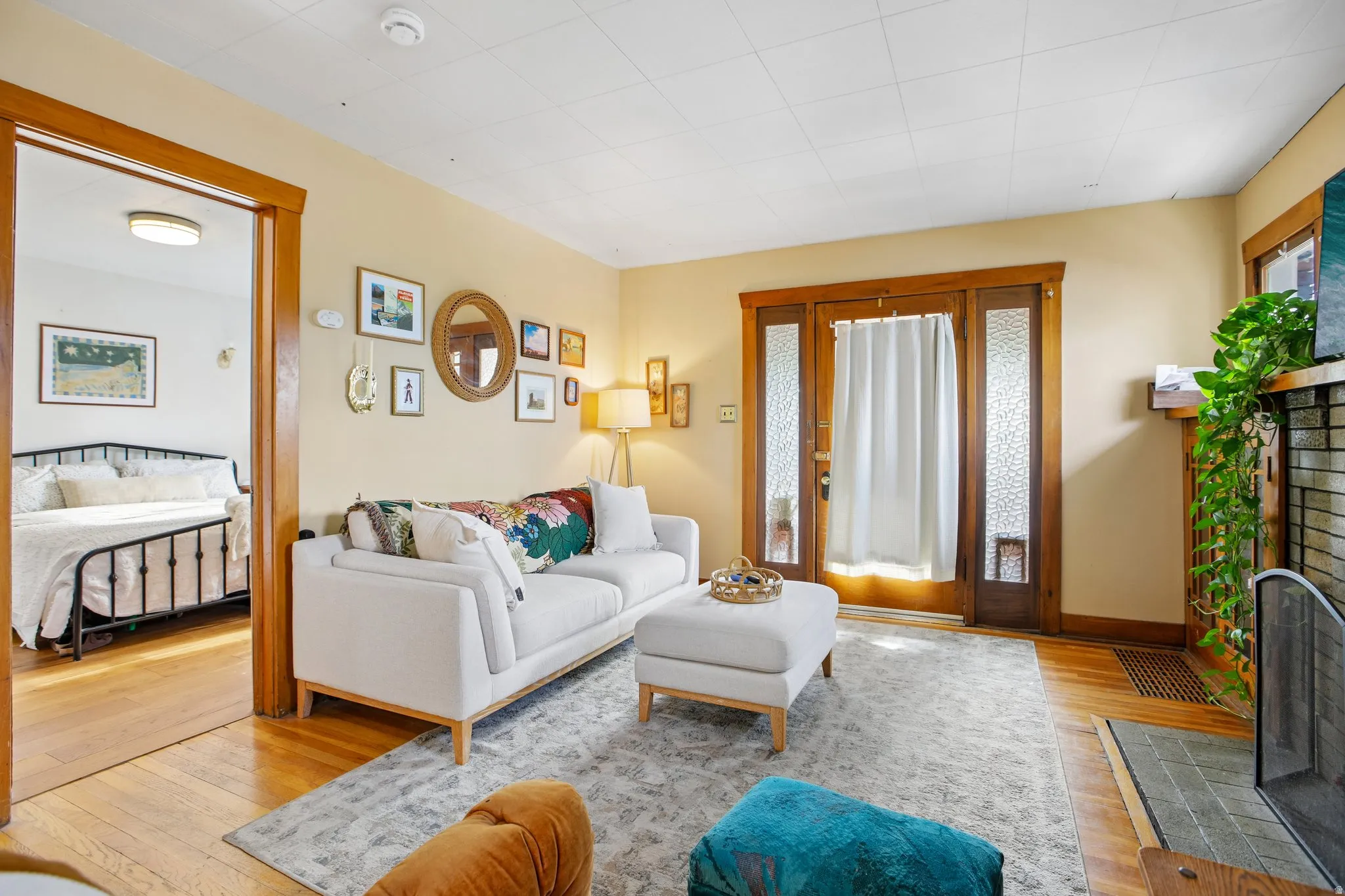 Hardwood flooring, wood trim, decorative fireplace, paneled ceiling, and a doorway with frosted glass panels