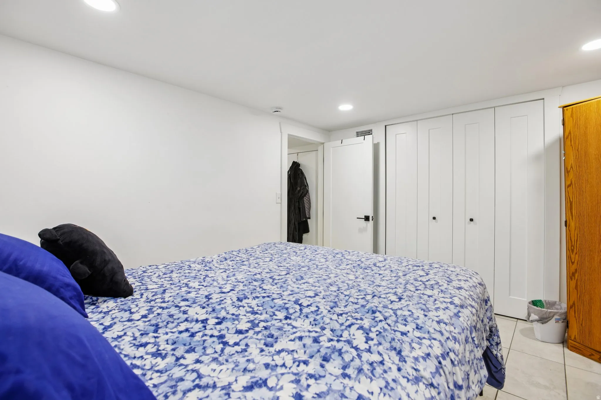 White walls, recessed lighting, white paneled doors, white bi-fold closet doors, and tile flooring