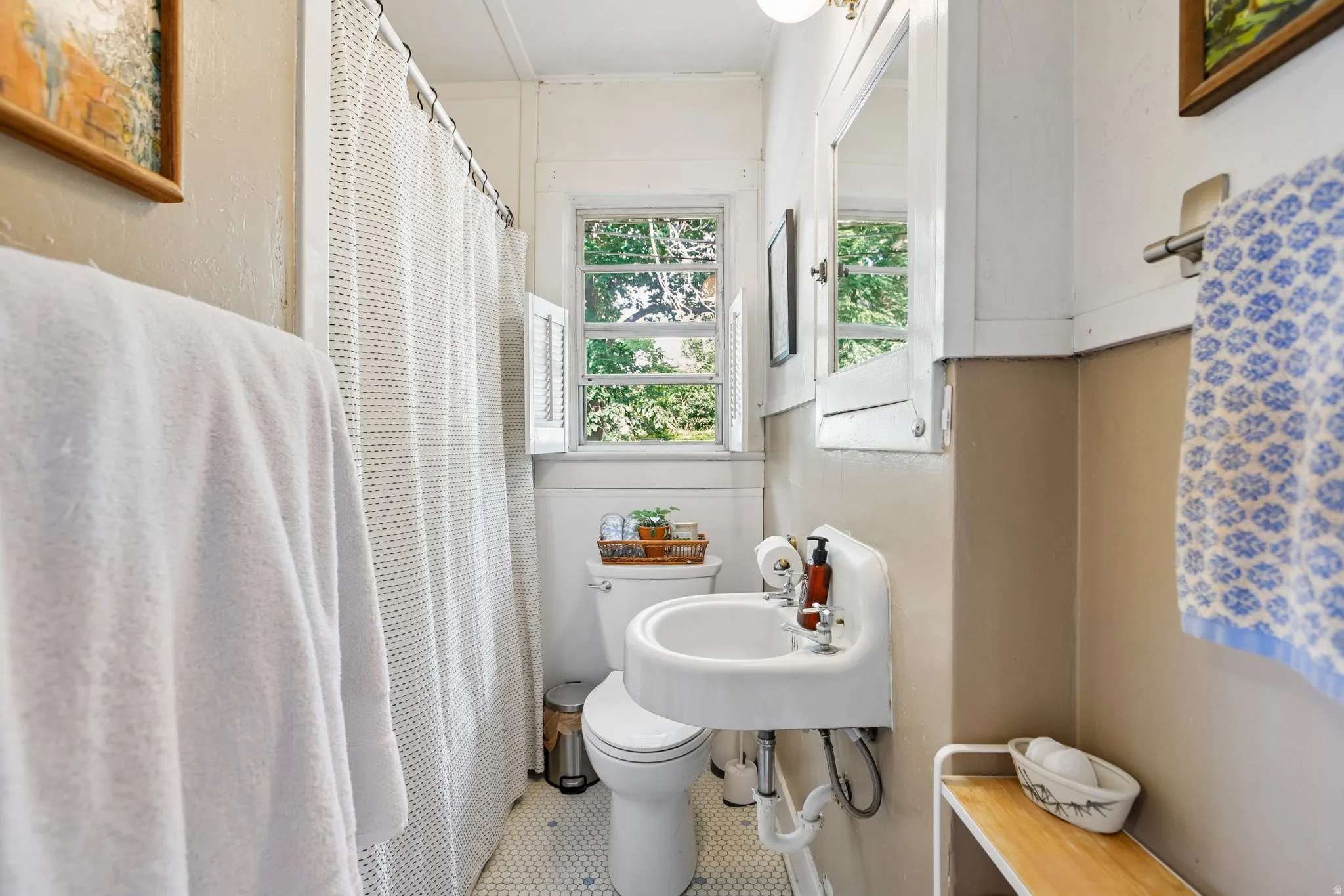 White porcelain pedestal sink, white toilet, white wall-mounted medicine cabinet, and hexagonal floor tile