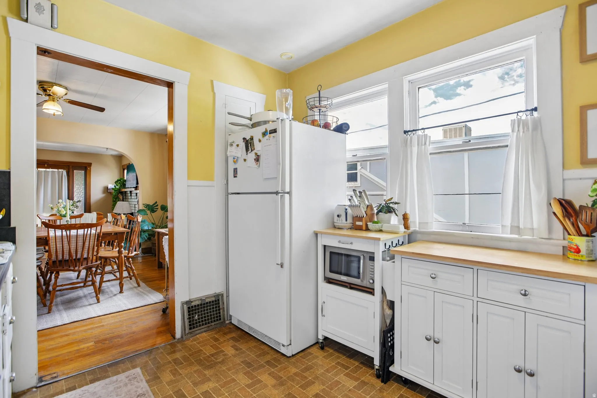 Kitchen featuring white cabinetry, wood-finish countertops, and dual windows