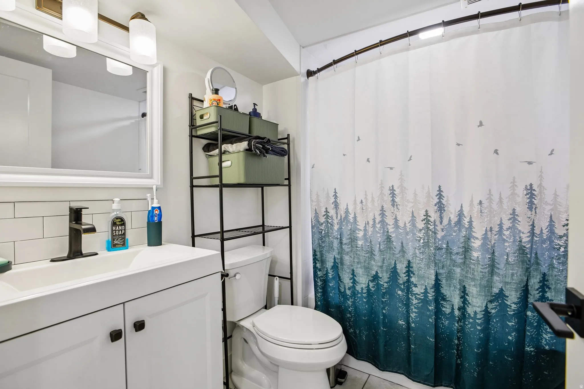 White vanity with a rectangular integrated sink, matte black faucet, subway tile backsplash, and overhead light fixture