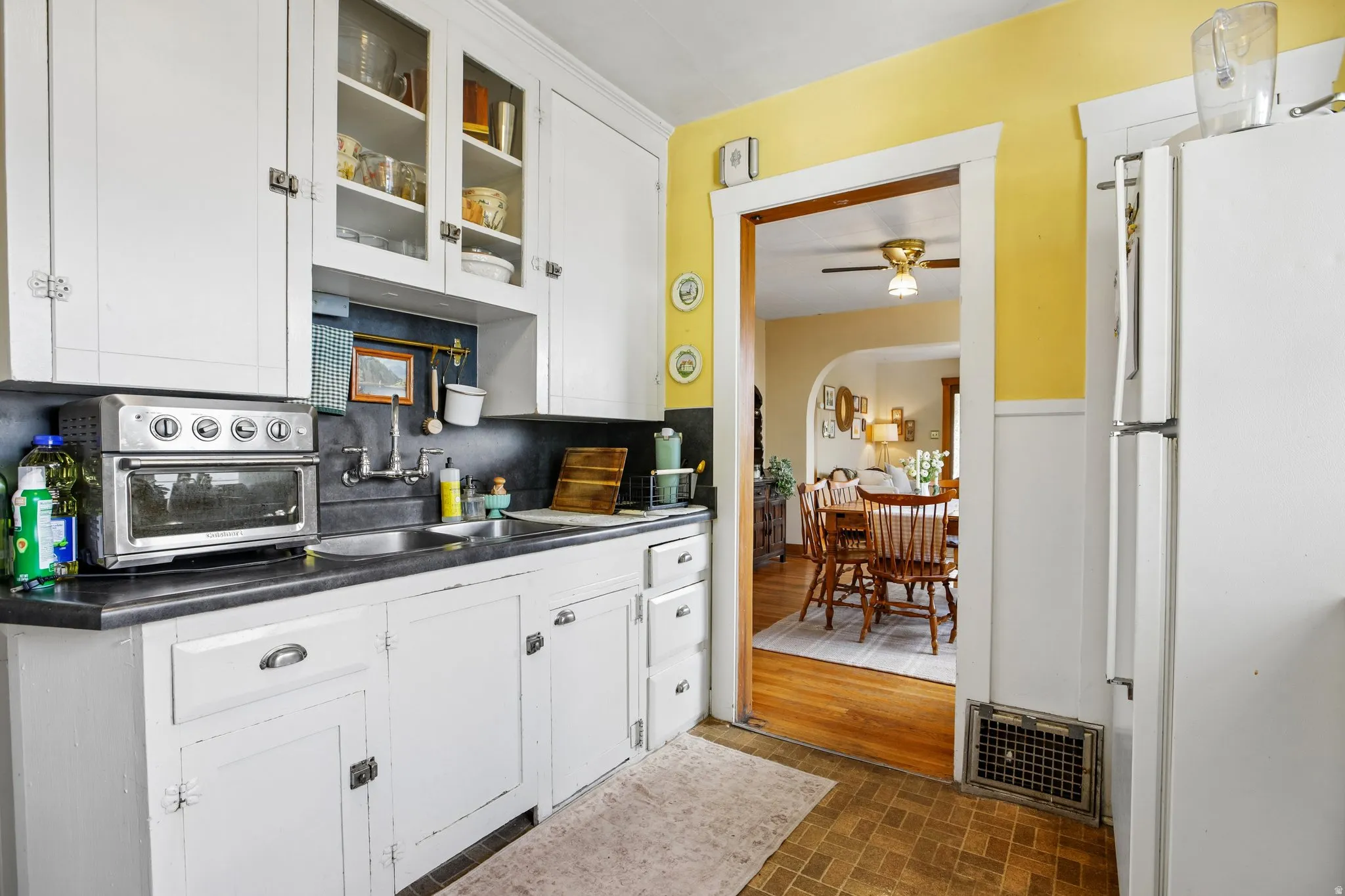 Kitchen featuring white cabinetry, dark countertops, and a stainless steel sink