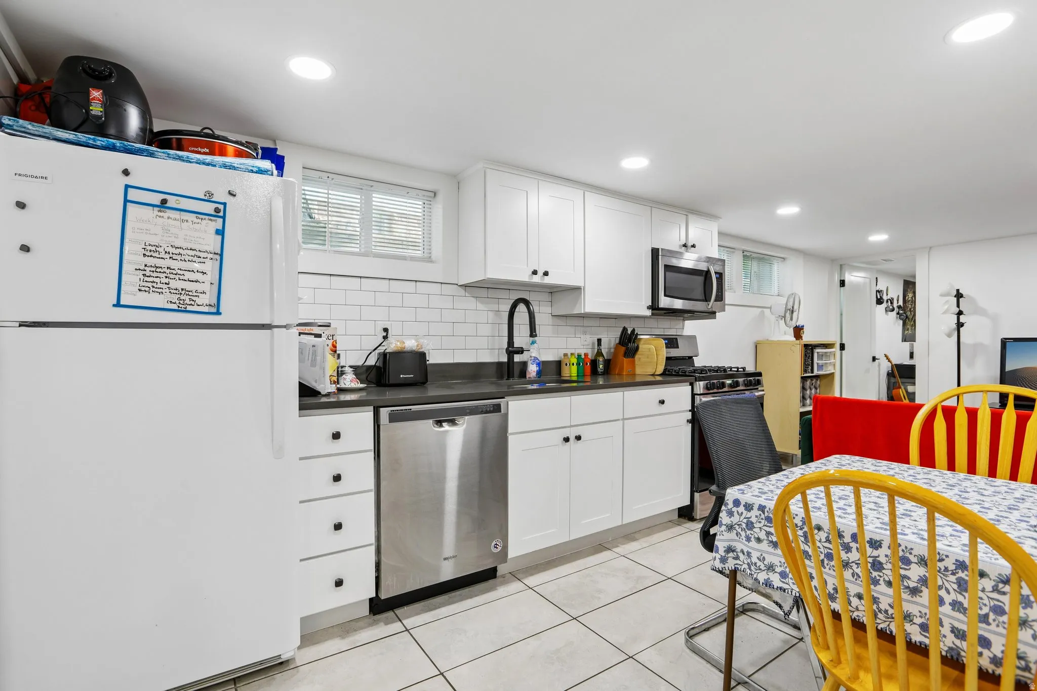 Kitchen featuring white cabinetry, subway tile backsplash, dark countertops, stainless steel appliances, and recessed lighting