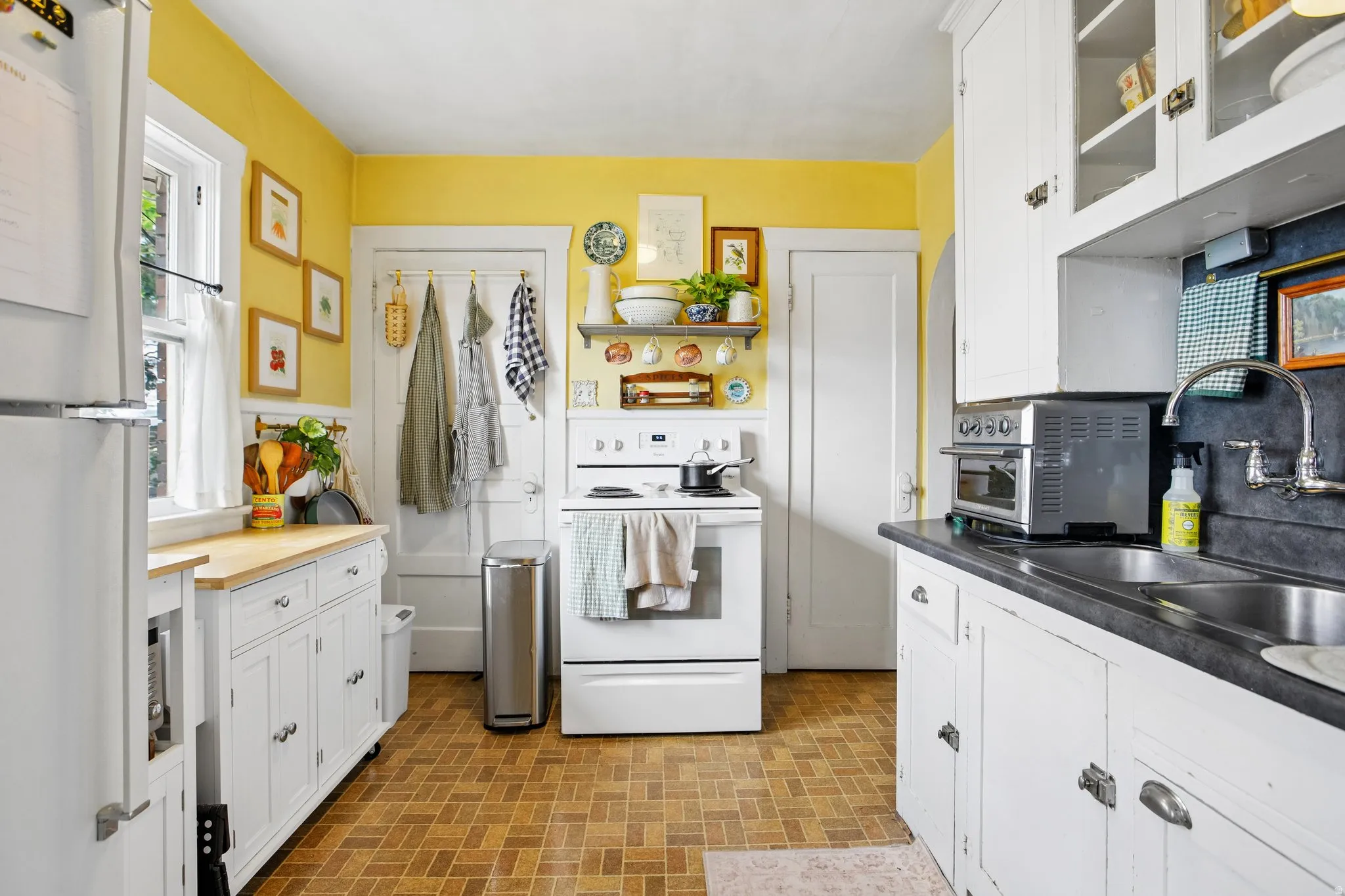 Kitchen featuring white cabinetry, wood-finish flooring, a double basin sink, and a window for natural light