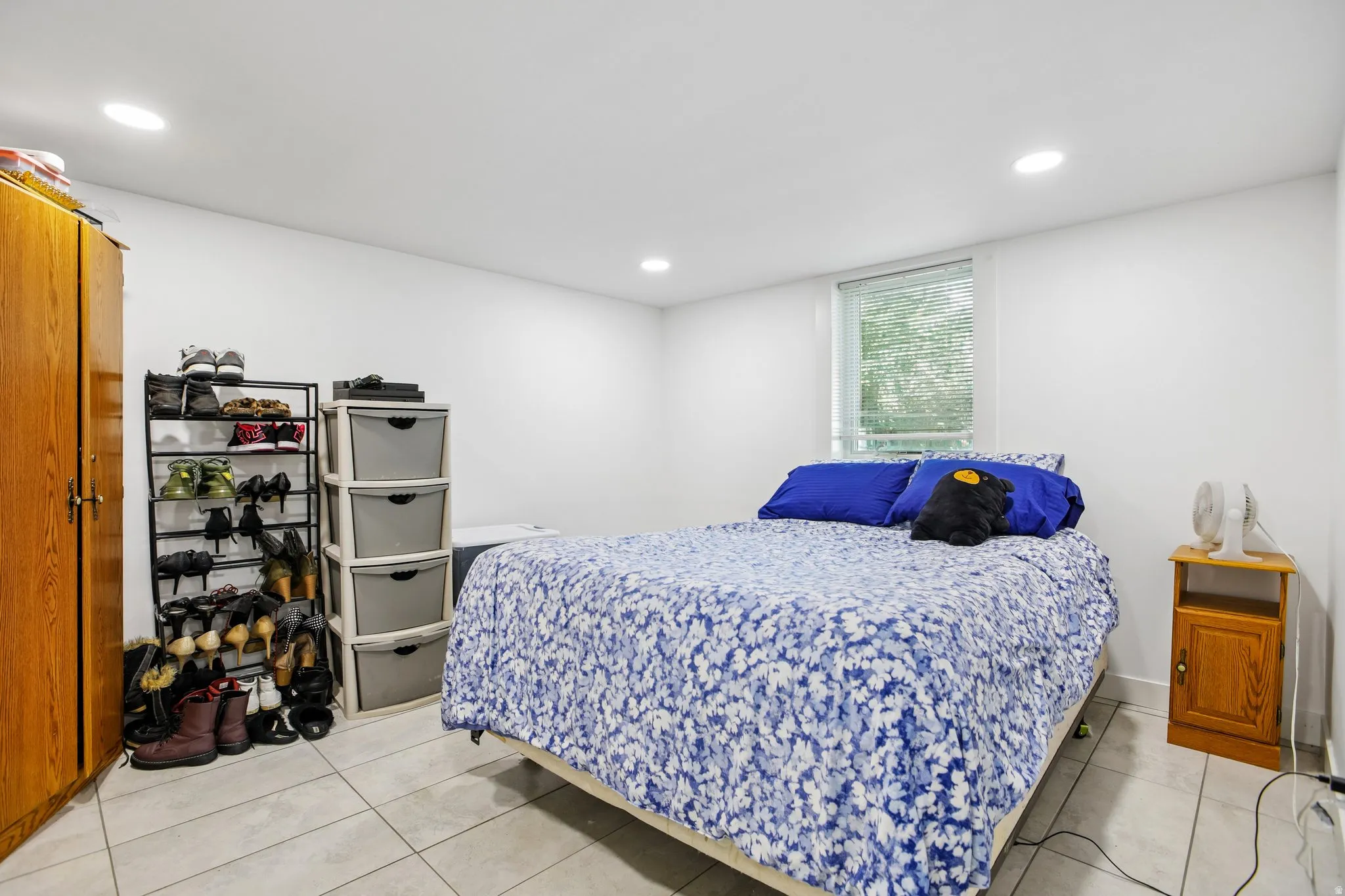 Recessed ceiling lighting, tiled flooring, wood-finish built-in wardrobe, and a window with blinds