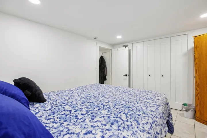 White walls, recessed lighting, white paneled doors, white bi-fold closet doors, and tile flooring