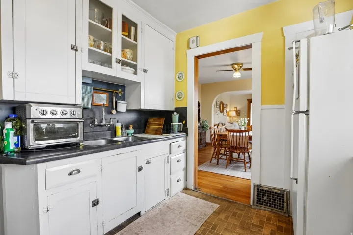 Kitchen featuring white cabinetry, dark countertops, and a stainless steel sink