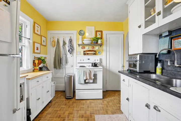 Kitchen featuring white cabinetry, wood-finish flooring, a double basin sink, and a window for natural light